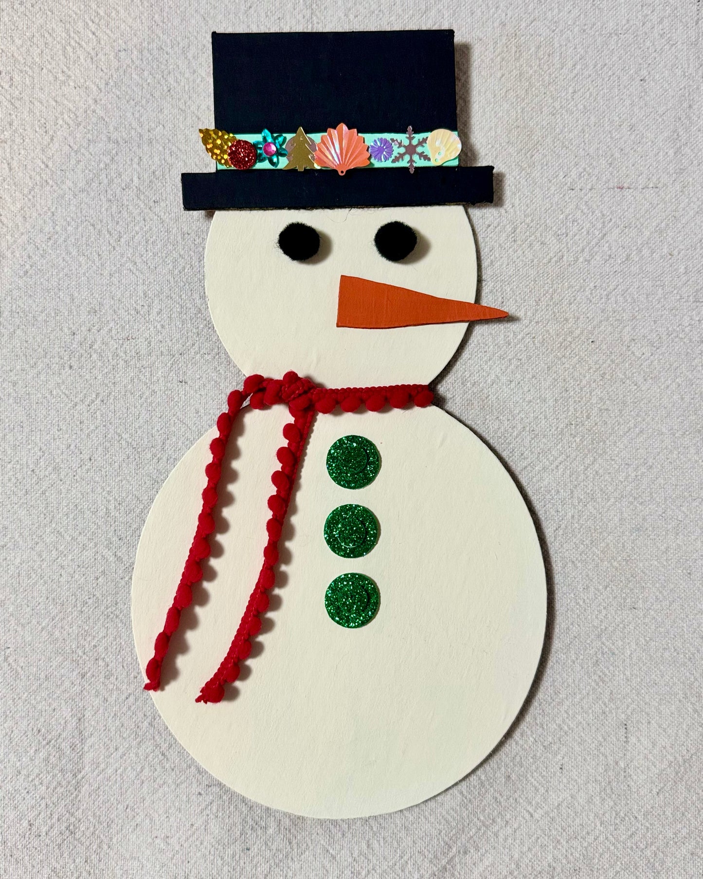 Completed Happy Snowman Craft Kit with a black top hat, red scarf, and green buttons.